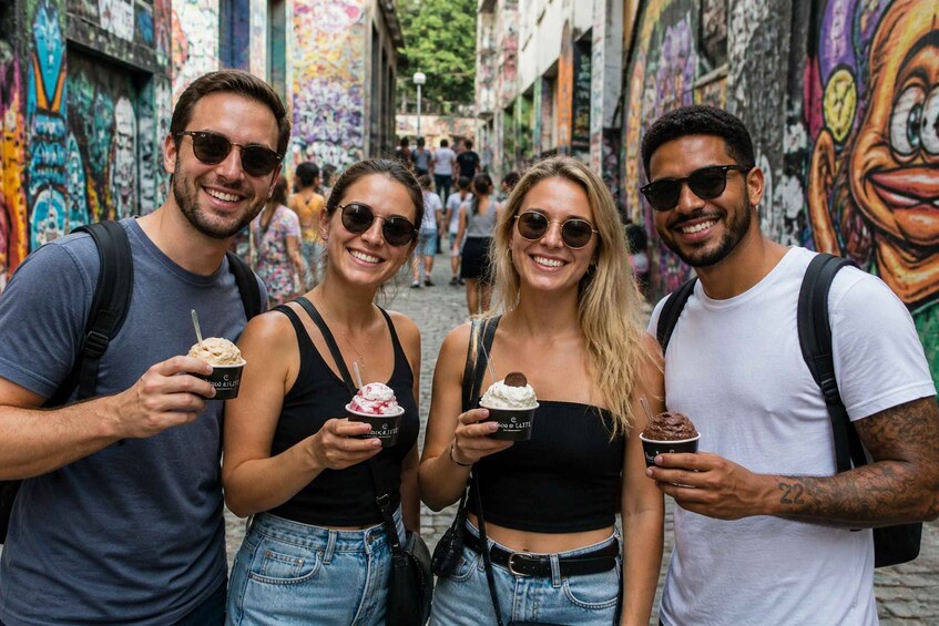 Four people holding ice cream cones in a street with colorful graffiti. 3