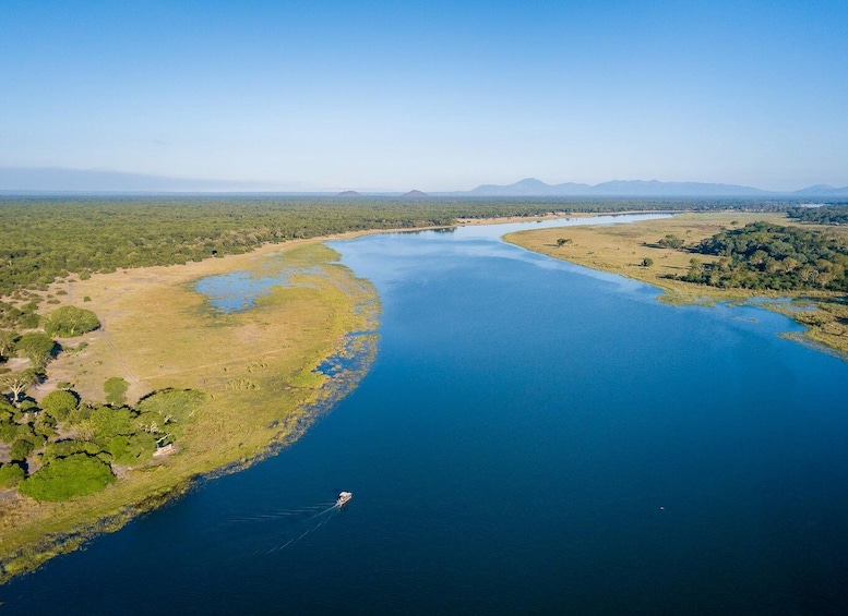 A river winding through a landscape with greenery and distant mountains. 1