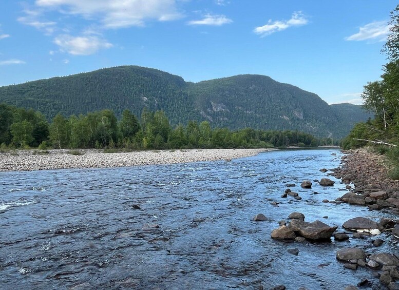 A river with rocks, surrounded by forested hills. 3