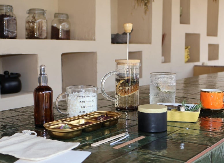 A kitchen counter with various cooking utensils, a measuring cup, a glass jar, and a tea infuser. 1