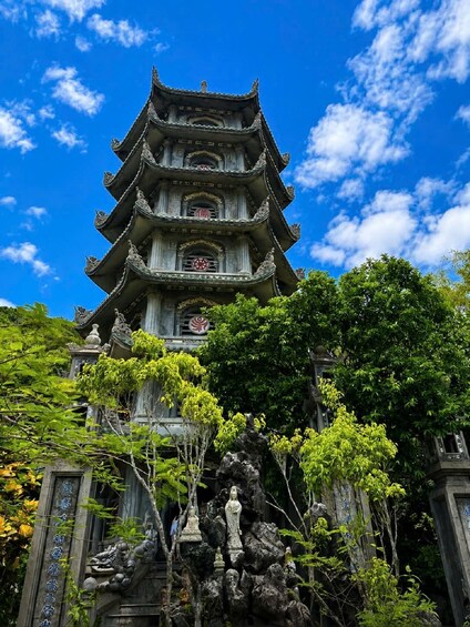 A multi-tiered pagoda with intricate carvings and a traditional roof, surrounded by lush greenery and trees. 4
