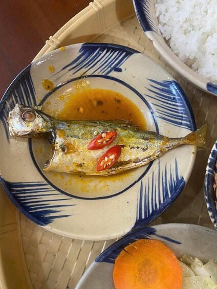 A plate with a fish, chili, and sauce, alongside a bowl of rice. 3