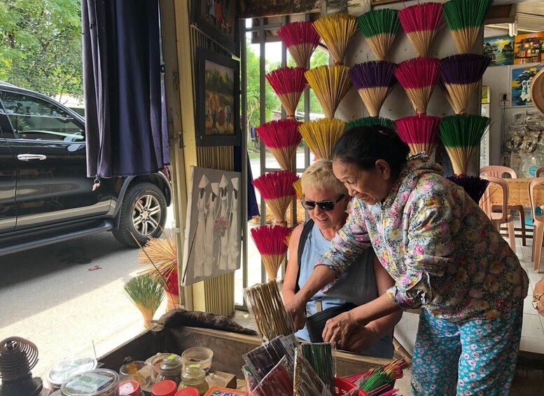 A street vendor stall with colorful brooms and various items for sale. 5