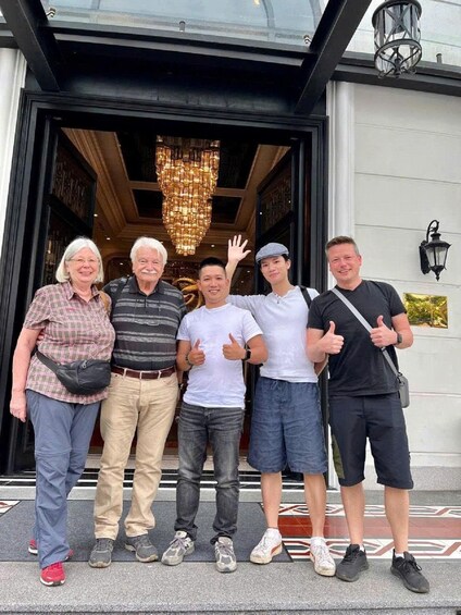 A group of people standing in front of a building with a large chandelier and a door. 3