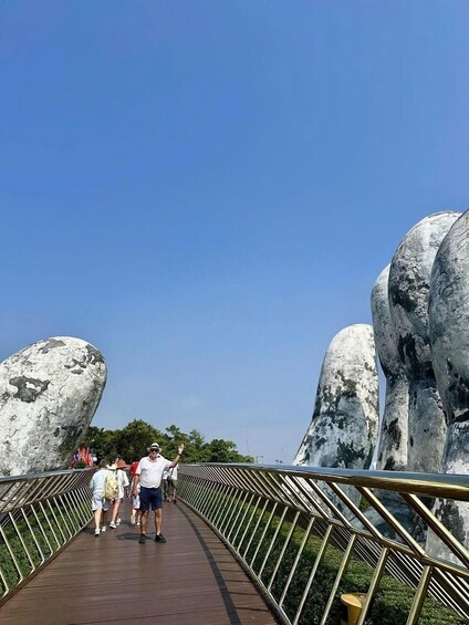 A wooden pedestrian bridge with metal railings, surrounded by large rock formations. 2
