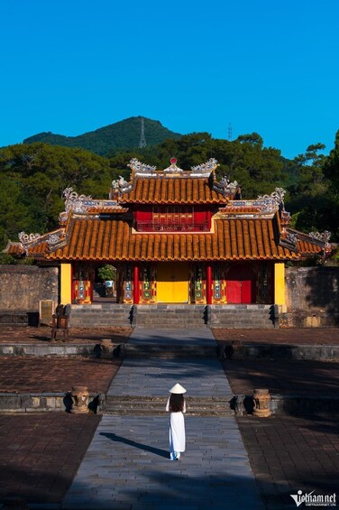 A traditional temple with ornate architecture, a clear sky, and a mountain in the background. 1