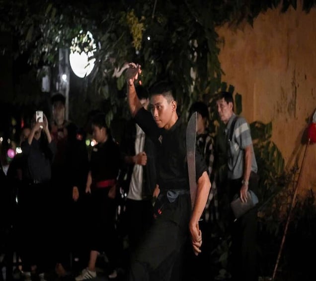 A person performing a martial arts demonstration outdoors at night. 4