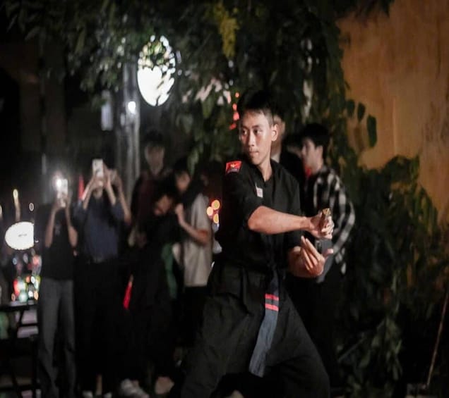 A martial artist performing in an outdoor setting with an audience. 5