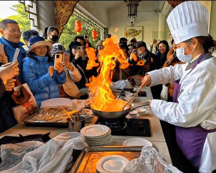 A chef cooking with flames in a wok, surrounded by an audience. 2