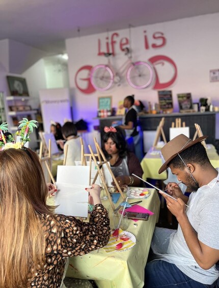 People painting at a table with a sign that reads 'Life is GOOD' in the background. 5