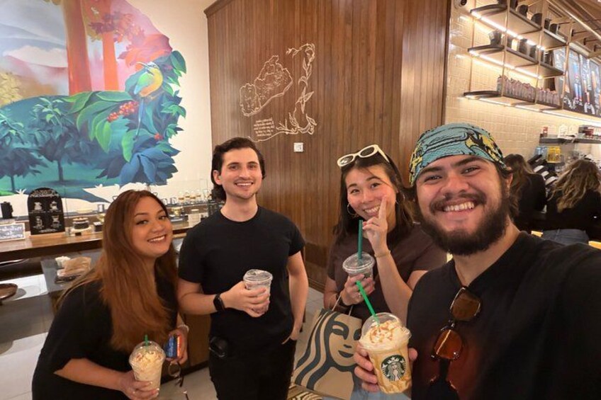 A group of people in a coffee shop holding drinks. 1