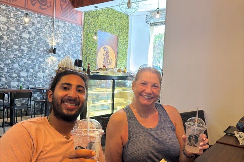 Two people sitting at a table in a cafe with drinks in plastic cups. 4
