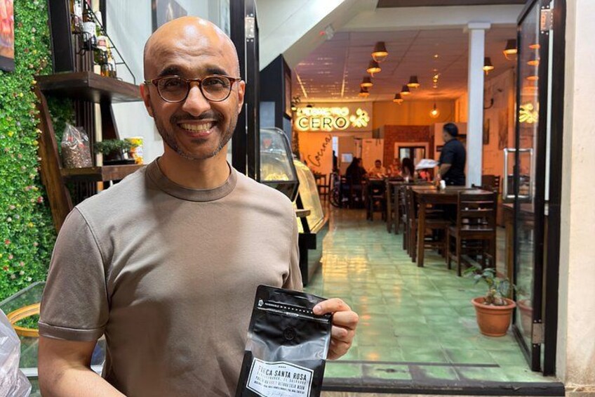 A person holding a product in front of a restaurant with a green interior and outdoor seating. 3