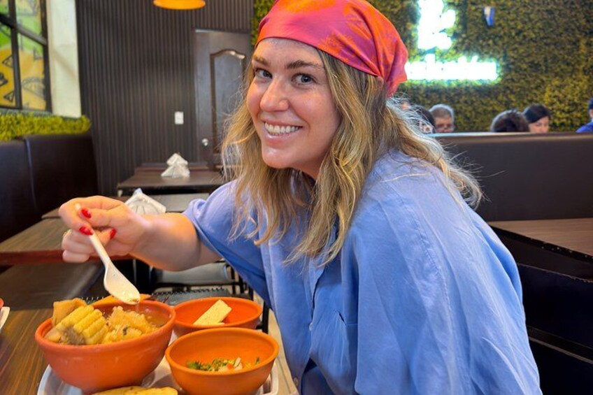 A person sitting at a table with bowls of food, wearing a blue shirt and a red headscarf. 5
