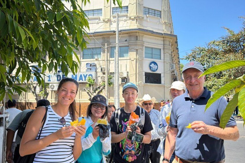 A group of people outdoors with a building in the background. 2