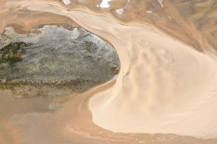 A vast desert landscape with a large body of water and a prominent sand dune. 1