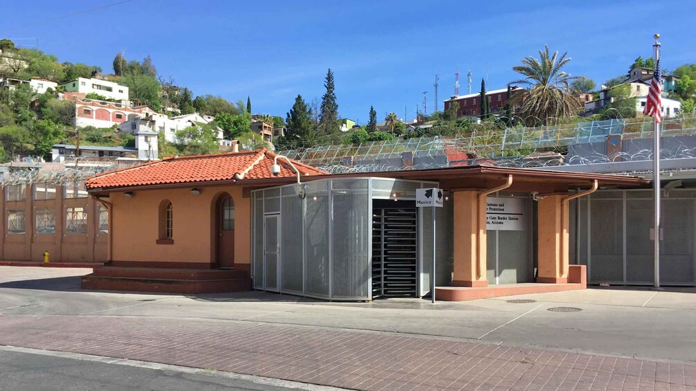 A small building with a red-tiled roof, a metal fence with barbed wire, and a sign indicating a Customs and Border Protection station in Arizona. 4