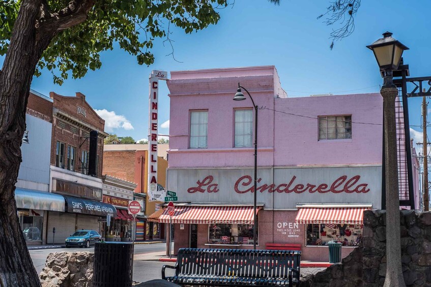 A pink building with 'La Cinderella' signage, a bench, and a street lamp. 5