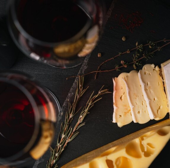 A cheese platter with slices, a knife, and rosemary sprigs on a dark surface. 2