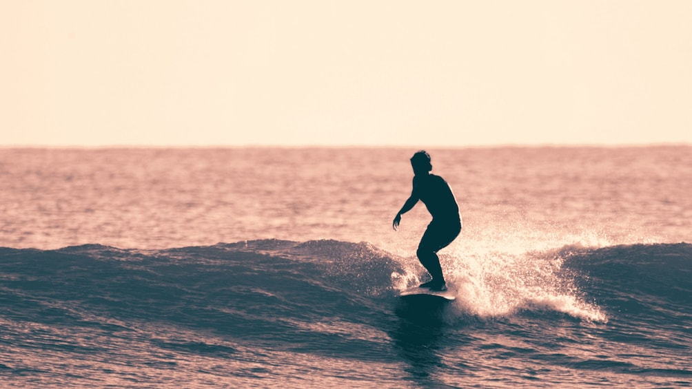 A silhouette of a person surfing on a wave. 1