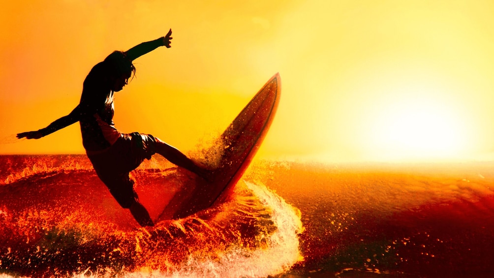 A silhouette of a person surfing a wave at sunset. 3