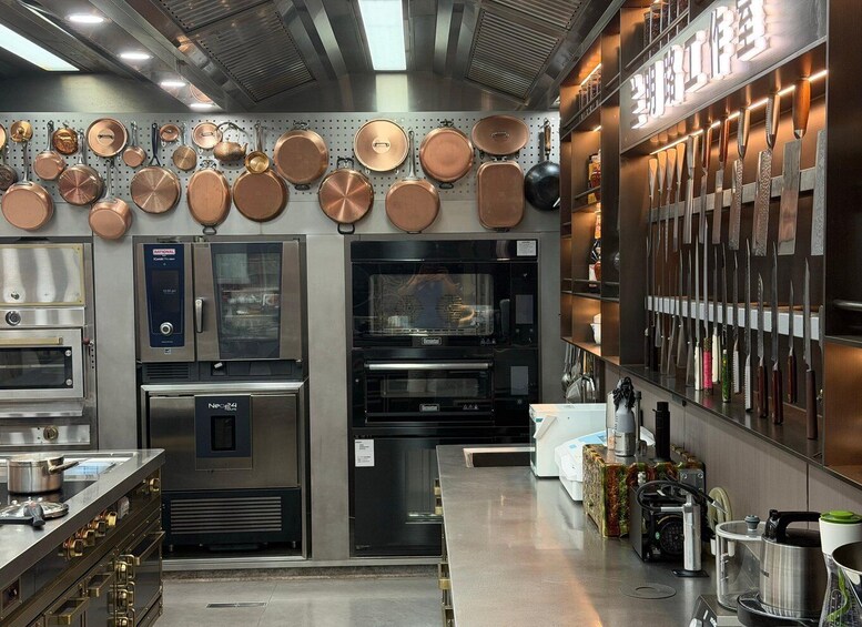 A commercial kitchen with stainless steel appliances, copper cookware, and a variety of knives on display. 5