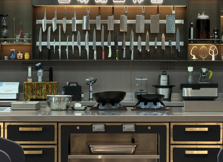 A kitchen with various knives on display, a coffee machine, and a wok on the counter. 1
