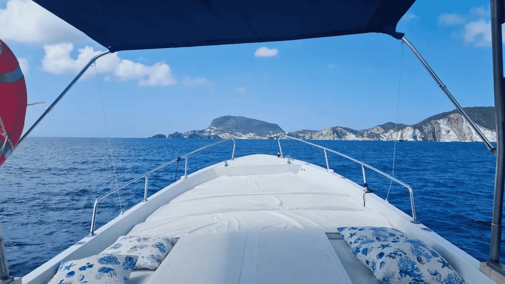 A boat's deck with a view of the sea and a mountainous coastline. 2