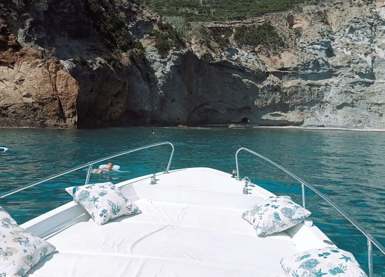 A boat with white cushions and a person swimming in the water. 1