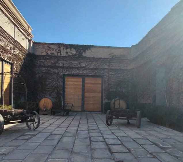 A courtyard with stone paving, a wooden door, and two wooden barrels. 3