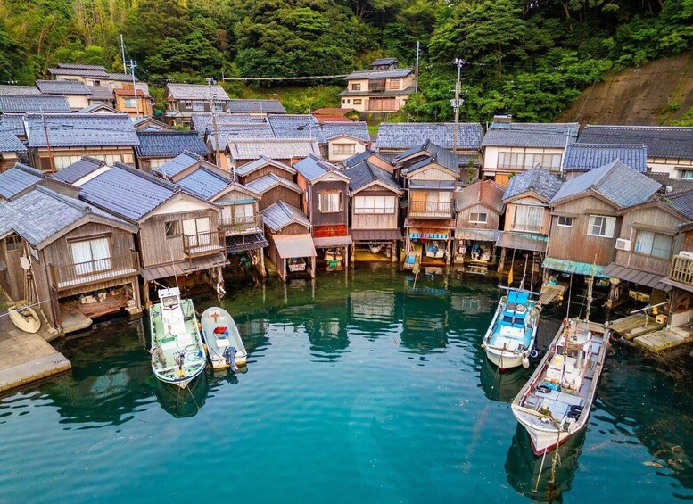 A traditional Japanese village with wooden houses and boats docked in a calm river. 5