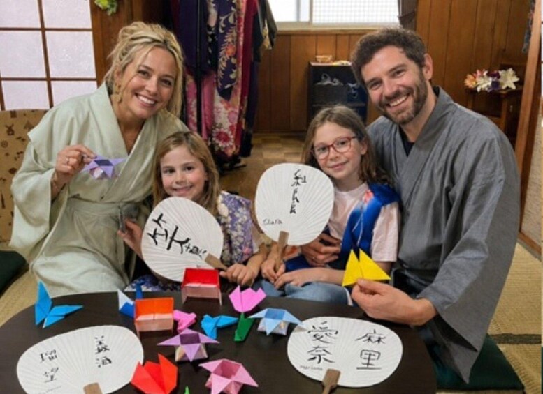 A family sitting at a table with origami figures and paper fans. 1