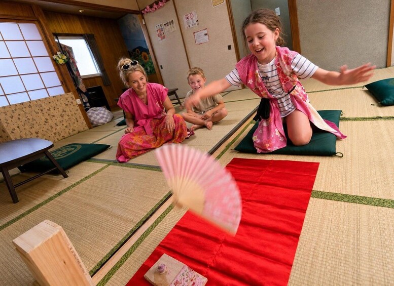 A tatami mat room with a fan, cushions, and a small table. 5