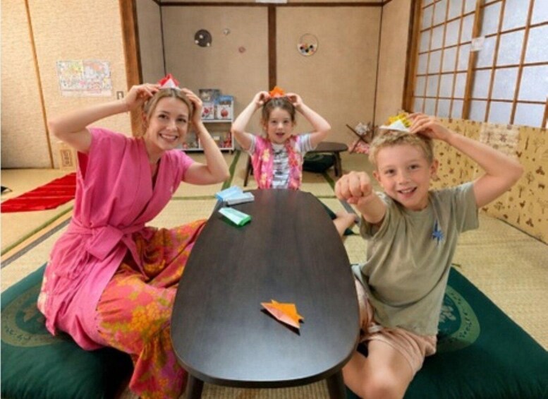 Three people sitting on tatami mats around a low table with a paper airplane. 2