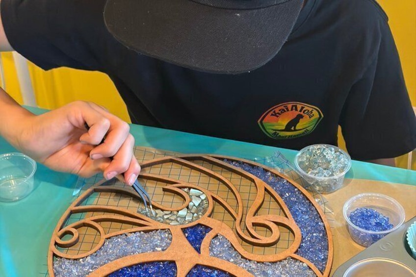 A person working on a decorative item with a grid pattern and glitter. 4