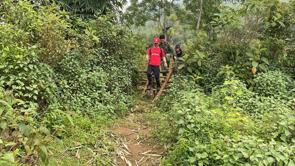 Two individuals crossing a forested area on a makeshift bridge. 2
