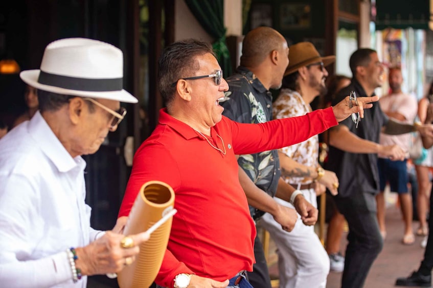 A group of people outdoors, some holding drinks and one pointing. 1