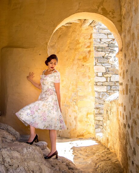 A woman in a floral dress standing in a stone archway. 5