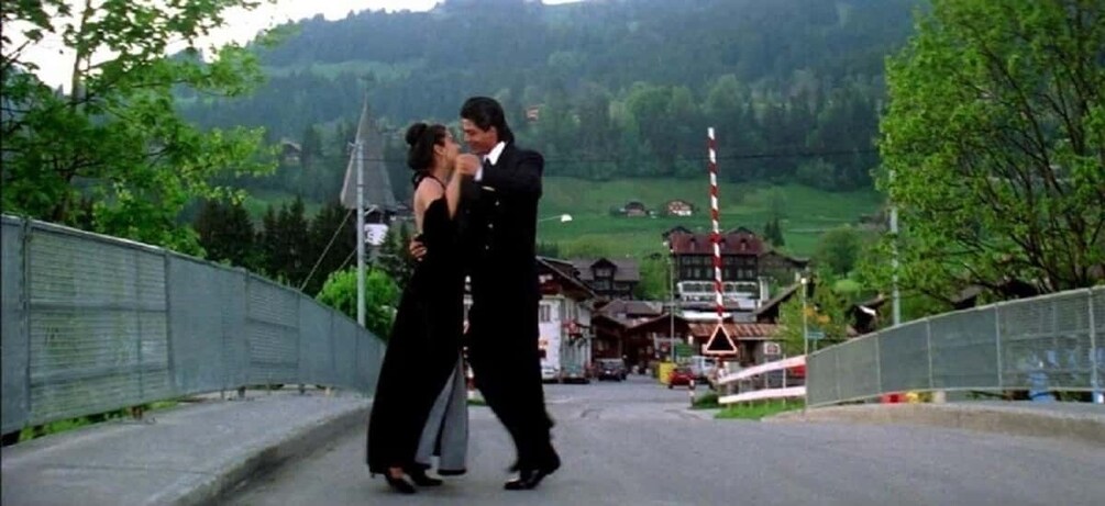 A couple dancing on a bridge with a mountainous landscape in the background. 3