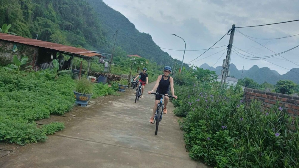 Two cyclists on a rural path surrounded by greenery and hills. 4