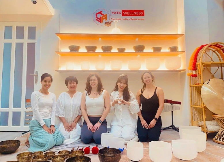 A group of people in a wellness center with meditation bowls and a logo for 'YATA WELLNESS.' 3