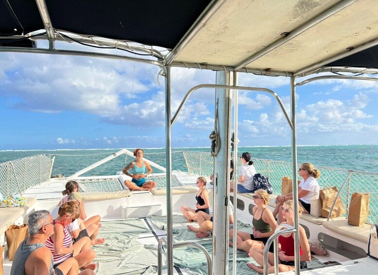 A group of people sitting on a boat deck with a view of the ocean. 1
