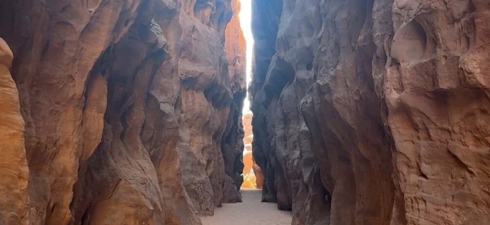 A narrow canyon with towering rock walls and a visible light source at the end. 4