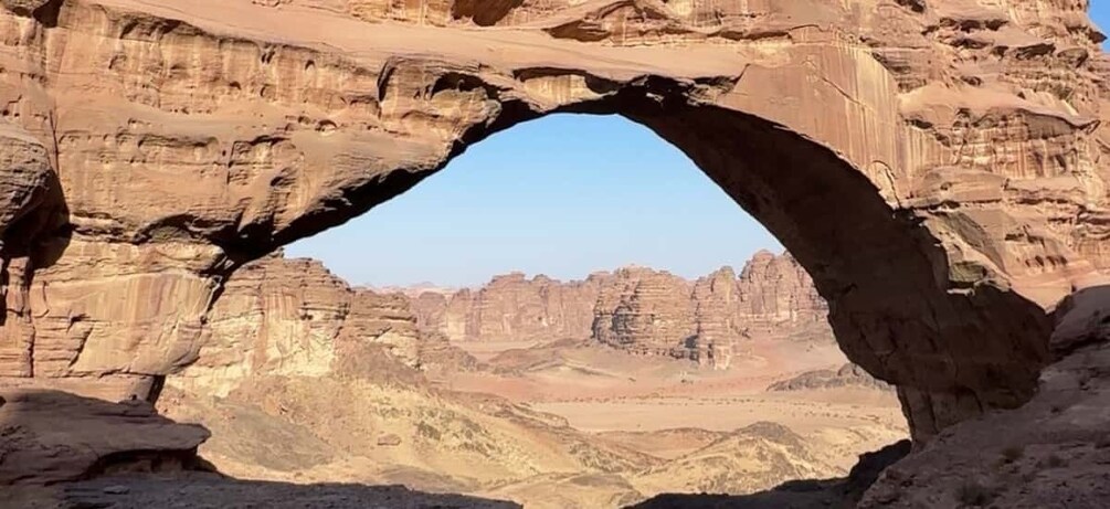 A natural rock arch formation with a desert landscape in the background. 1