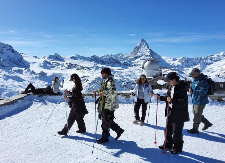 A group of people hiking on a snowy mountain with a prominent peak in the background. 1