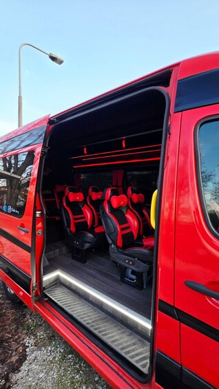 A red van with its rear door open, revealing the interior with red and black seats and a metal step leading to the back. 3