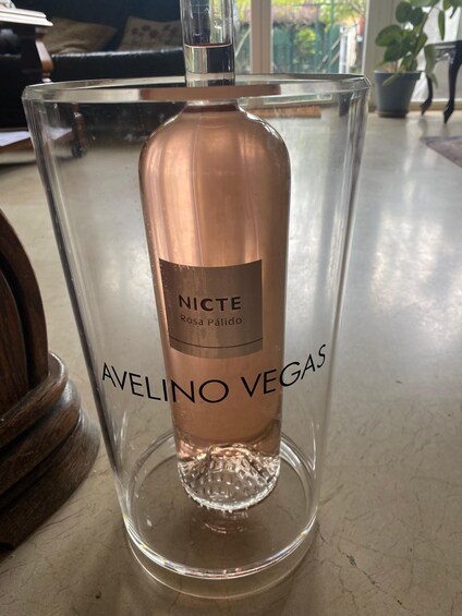 A bottle of NICTE Rosa Pálido Avelino Vegas inside a clear glass container. 3