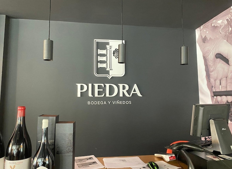 A wine shop interior with a logo, bottles, a desk, computer, and a poster. 5