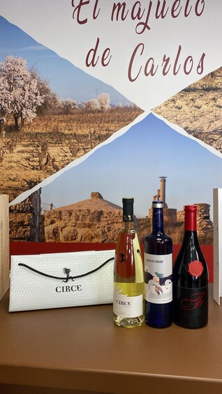 Three wine bottles and a branded box against a backdrop of a vineyard. 4