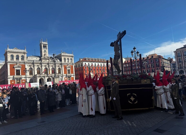 A historical reenactment with participants in period costumes, a religious statue, and a prominent church in the background. 5